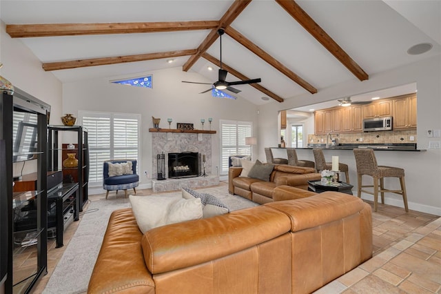 315 Ridge Rd, Palm Harbor, FL 34683 - living room featuring a ceiling fan, high vaulted ceiling, beamed ceiling, a stone fireplace, and baseboards