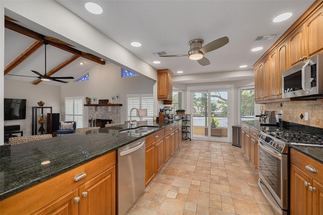 315 Ridge Rd, Palm Harbor, FL 34683 - kitchen featuring appliances with stainless steel finishes, a ceiling fan, a sink, a fireplace, and decorative backsplash