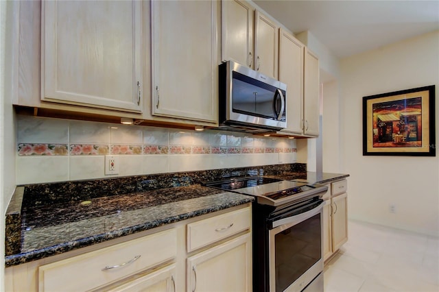 kitchen featuring stainless steel appliances, decorative backsplash, and dark stone counters