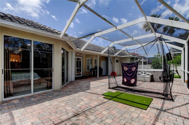 view of patio featuring a hot tub and glass enclosure