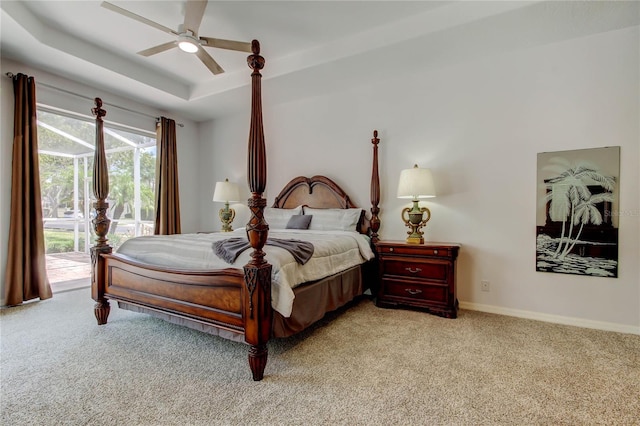 bedroom with light carpet, access to outside, a raised ceiling, and baseboards