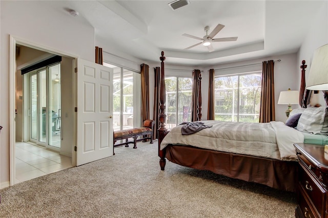 carpeted bedroom featuring access to outside, a raised ceiling, and ceiling fan