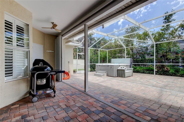 view of patio featuring a hot tub, ceiling fan, area for grilling, and glass enclosure