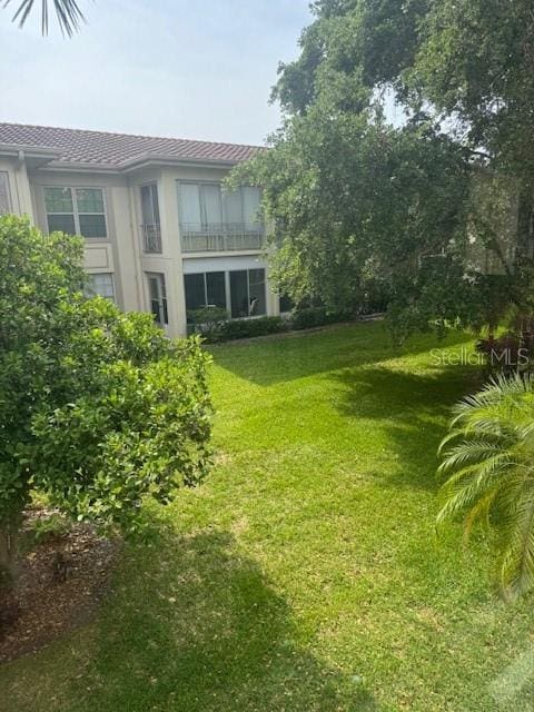 view of grassy yard featuring a balcony