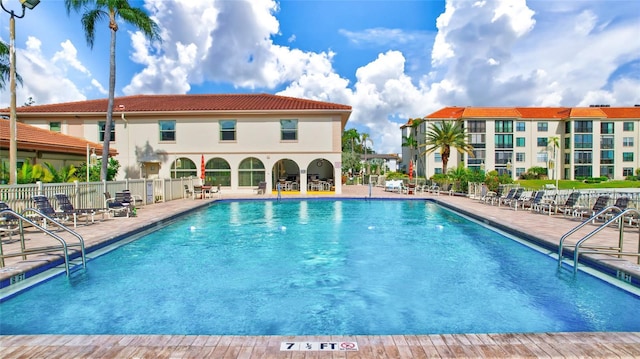 community pool with a patio and fence
