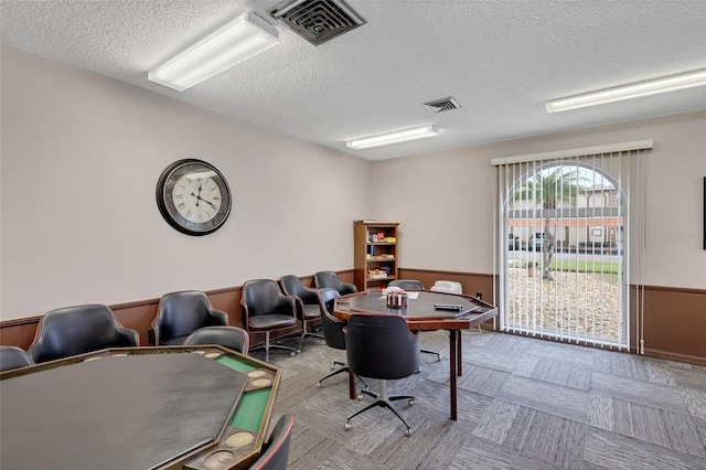 office space with a textured ceiling, a wainscoted wall, carpet, and wood walls