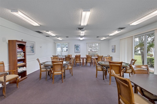 dining space featuring a textured ceiling and dark colored carpet