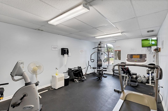 exercise room with a drop ceiling and baseboards