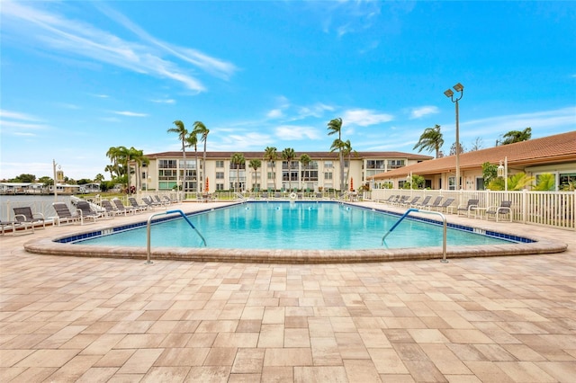 community pool with a patio area and fence