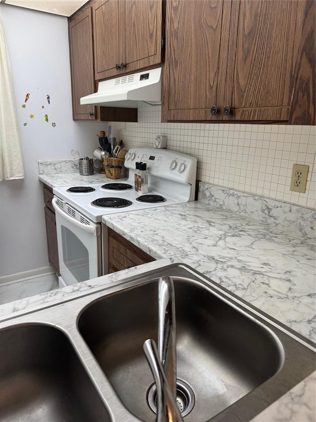 kitchen featuring electric stove, under cabinet range hood, tasteful backsplash, and baseboards