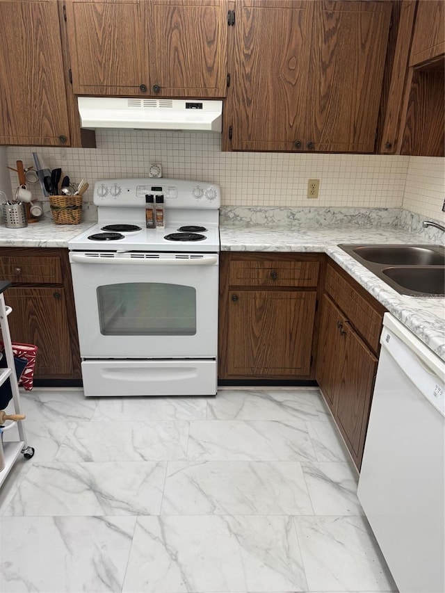 kitchen featuring white appliances, under cabinet range hood, light marble finish flooring, a sink, and decorative backsplash