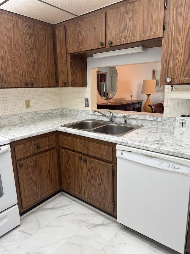 kitchen featuring white dishwasher, a sink, light marble finish flooring, light countertops, and tasteful backsplash