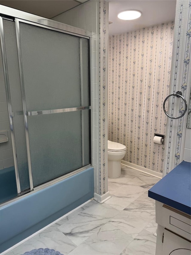 bathroom featuring marble finish floors, enclosed tub / shower combo, toilet, vanity, and baseboards