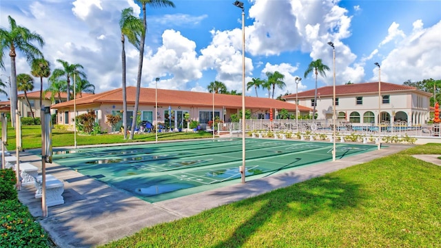 surrounding community featuring fence, shuffleboard, and a lawn