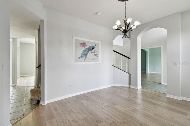 27012 Sea Breeze Way, Wesley Chapel, FL 33544 - empty room with stairway, arched walkways, light wood-style floors, and a chandelier
