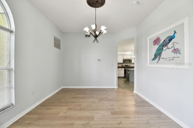 27012 Sea Breeze Way, Wesley Chapel, FL 33544 - unfurnished dining area featuring a chandelier, light wood finished floors, and baseboards