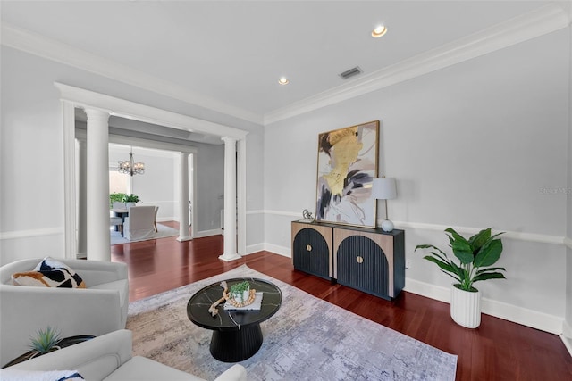 living area featuring ornate columns, wood finished floors, a chandelier, ornamental molding, and baseboards