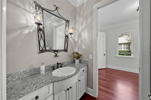bathroom with ornamental molding, wood finished floors, vanity, and baseboards