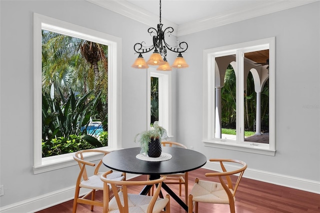dining room featuring crown molding, healthy amount of natural light, wood finished floors, baseboards, and a chandelier