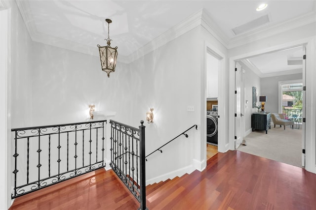 staircase featuring wood finished floors, washer / clothes dryer, baseboards, and ornamental molding