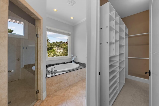 bathroom with a shower stall, a walk in closet, a bath, ornamental molding, and tile patterned flooring