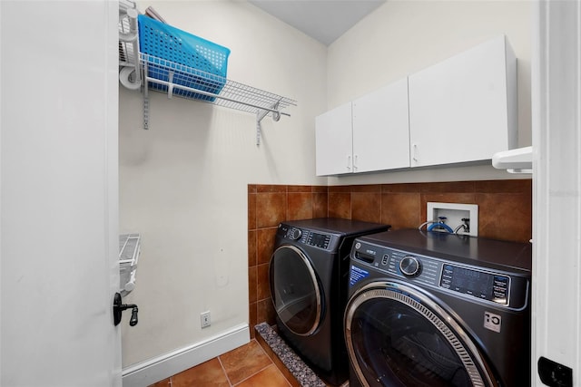 clothes washing area with washing machine and clothes dryer, cabinet space, and tile patterned flooring