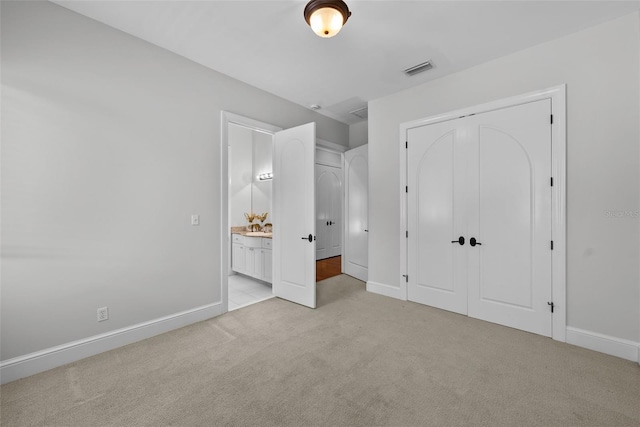 unfurnished bedroom with light carpet, baseboards, connected bathroom, and a closet