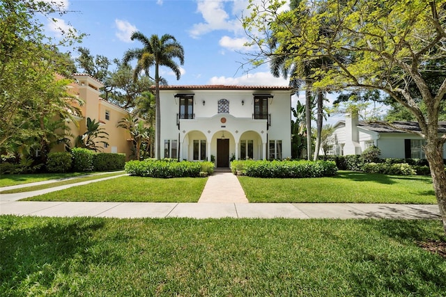 mediterranean / spanish house featuring a front lawn, a balcony, and stucco siding