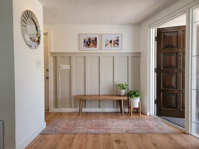7092 S Shore Dr S, Saint Petersburg, FL 33707 - mudroom with wood finished floors, a decorative wall, a textured ceiling, and wainscoting