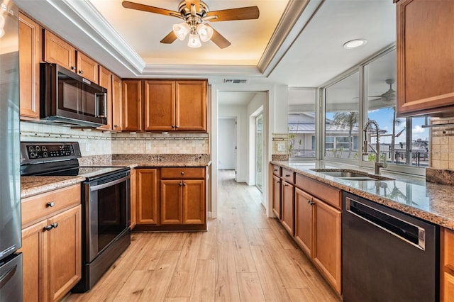 7092 S Shore Dr S, Saint Petersburg, FL 33707 - kitchen with stainless steel appliances, a sink, a raised ceiling, light wood-type flooring, and backsplash