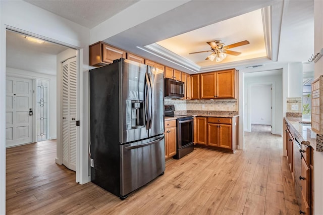 7092 S Shore Dr S, Saint Petersburg, FL 33707 - kitchen with appliances with stainless steel finishes, a tray ceiling, light wood-style floors, and light stone countertops