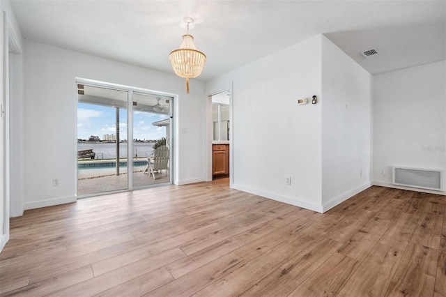 7092 S Shore Dr S, Saint Petersburg, FL 33707 - spare room with a chandelier, light wood-style floors, baseboards, and a water view