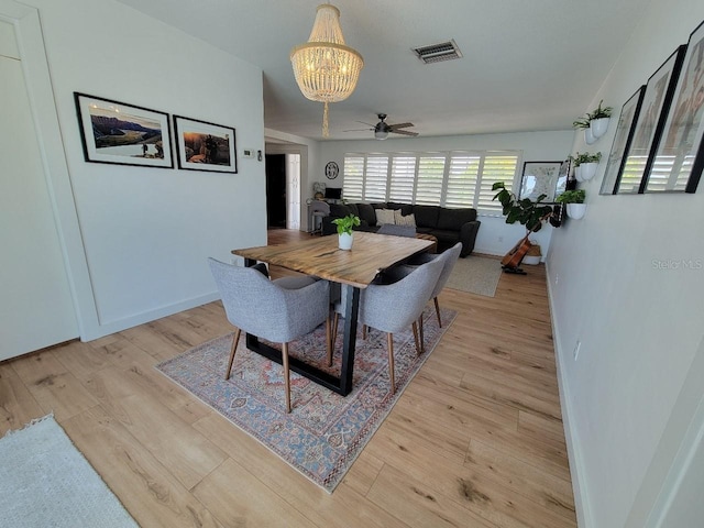 7092 S Shore Dr S, Saint Petersburg, FL 33707 - dining room with a chandelier, light wood-style flooring, a ceiling fan, and baseboards