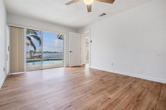 7092 S Shore Dr S, Saint Petersburg, FL 33707 - spare room featuring ceiling fan, light wood-type flooring, baseboards, and a water view