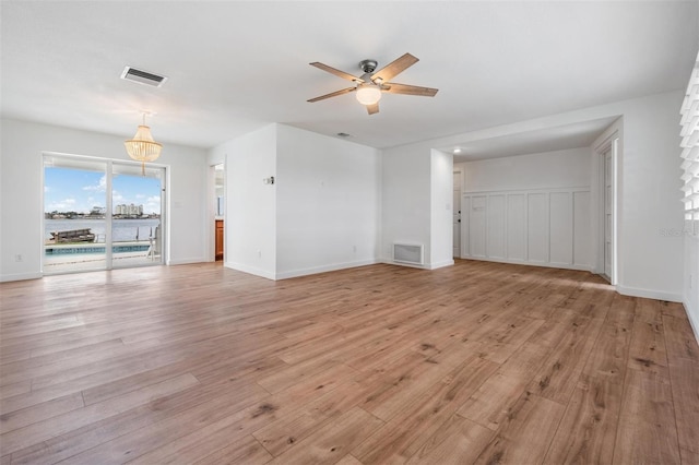 7092 S Shore Dr S, Saint Petersburg, FL 33707 - unfurnished living room with a ceiling fan, light wood-style flooring, baseboards, and a water view