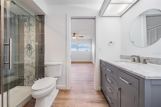 7092 S Shore Dr S, Saint Petersburg, FL 33707 - bathroom with wood finished floors, toilet, a ceiling fan, tiled shower, and vanity