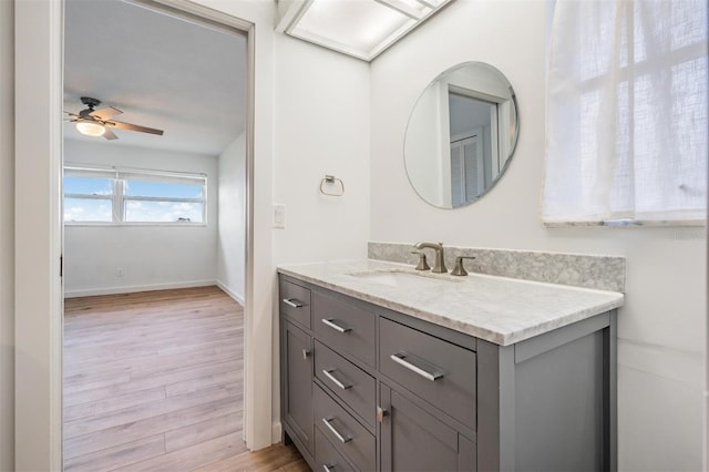 7092 S Shore Dr S, Saint Petersburg, FL 33707 - bathroom featuring wood finished floors, vanity, baseboards, and a ceiling fan