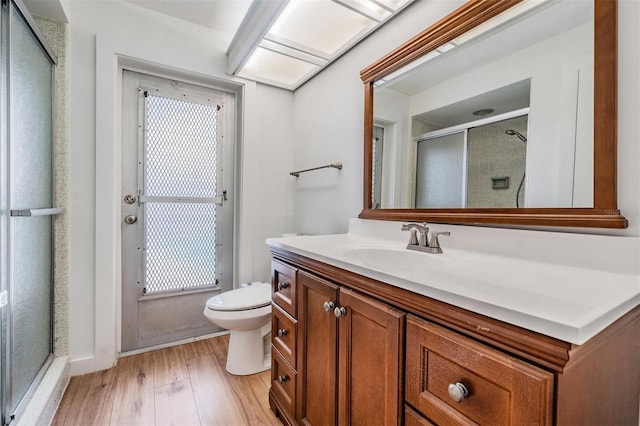7092 S Shore Dr S, Saint Petersburg, FL 33707 - bathroom featuring toilet, a shower stall, wood finished floors, and vanity