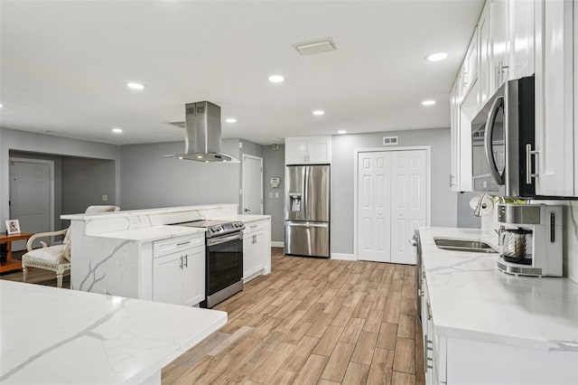 6010 Bayou Grande Blvd NE, Saint Petersburg, FL 33703 - kitchen with appliances with stainless steel finishes, island exhaust hood, light wood-style floors, recessed lighting, and a kitchen island