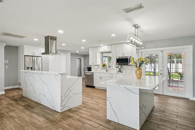 6010 Bayou Grande Blvd NE, Saint Petersburg, FL 33703 - kitchen with appliances with stainless steel finishes, island range hood, a large island, light wood-style flooring, and white cabinetry