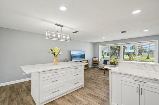 6010 Bayou Grande Blvd NE, Saint Petersburg, FL 33703 - kitchen with light wood finished floors, white cabinets, recessed lighting, decorative light fixtures, and light stone countertops