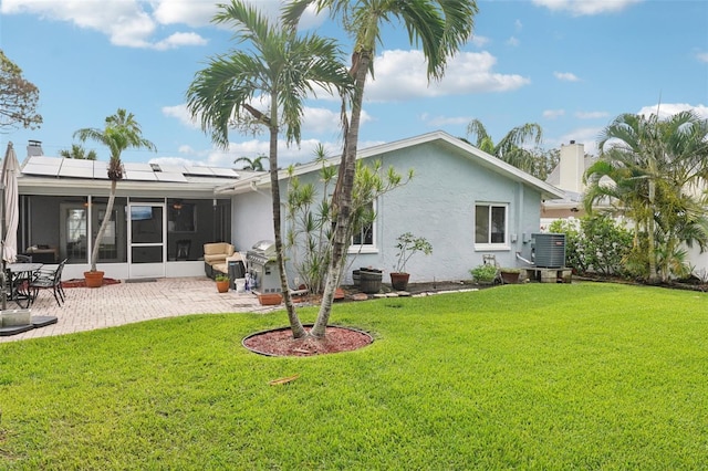6010 Bayou Grande Blvd NE, Saint Petersburg, FL 33703 - back of house with roof mounted solar panels, a yard, a sunroom, a patio area, and stucco siding