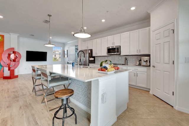 915 Tidewater Shores Loop, Bradenton, FL 34208 - kitchen featuring stainless steel appliances, crown molding, a breakfast bar, white cabinetry, and tasteful backsplash