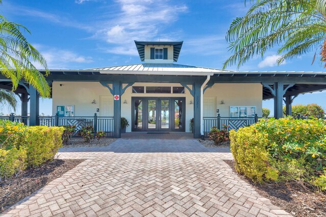 915 Tidewater Shores Loop, Bradenton, FL 34208 - property entrance with stucco siding, metal roof, french doors, and covered porch