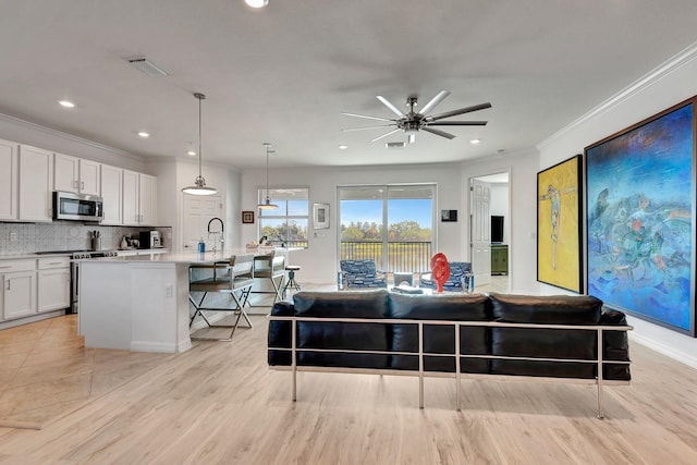 915 Tidewater Shores Loop, Bradenton, FL 34208 - living room with crown molding, ceiling fan, recessed lighting, light wood-style floors, and baseboards
