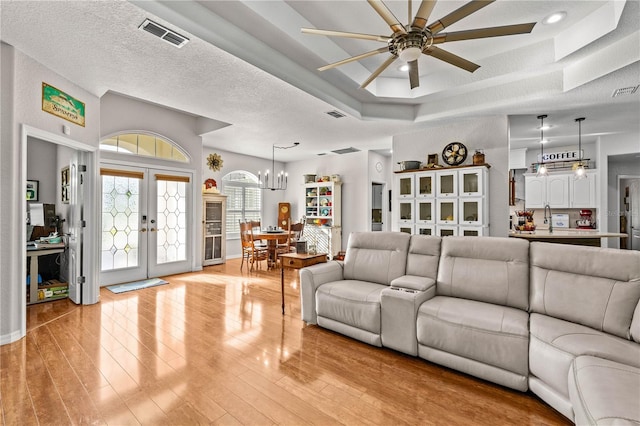 5296 Slater Rd, Spring Hill, FL 34608 - living area featuring ceiling fan, light wood-style flooring, french doors, a chandelier, and a raised ceiling