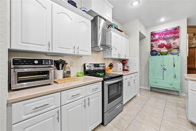 5296 Slater Rd, Spring Hill, FL 34608 - kitchen with stainless steel range with electric stovetop, wall chimney exhaust hood, white cabinetry, light countertops, and light tile patterned flooring
