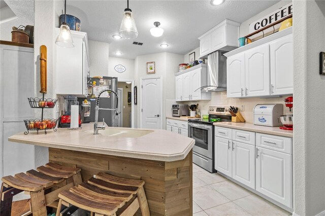 5296 Slater Rd, Spring Hill, FL 34608 - kitchen with electric range, wall chimney exhaust hood, a peninsula, and a breakfast bar area