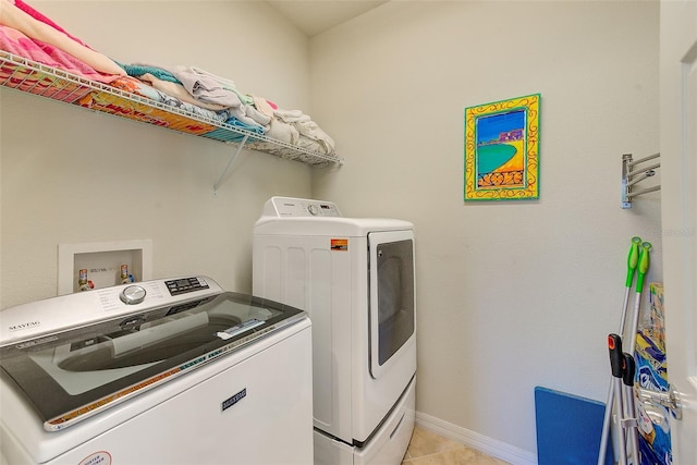 washroom featuring washing machine and dryer, light tile patterned floors, and baseboards