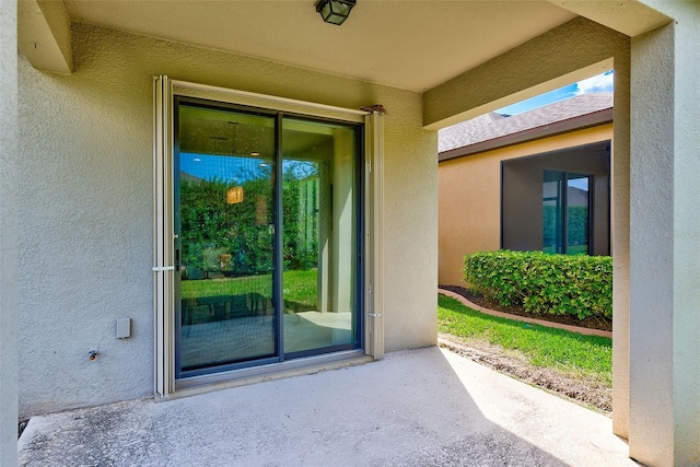 property entrance featuring stucco siding and a patio